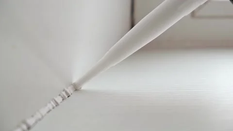 A man applies a sealant to the seam between the window and the sill from a tube Stock Footage 168323334