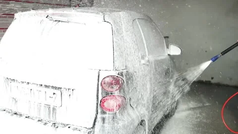 Man applying foam to black car in car wash. Car wash service with self-service Stock Footage 304813450