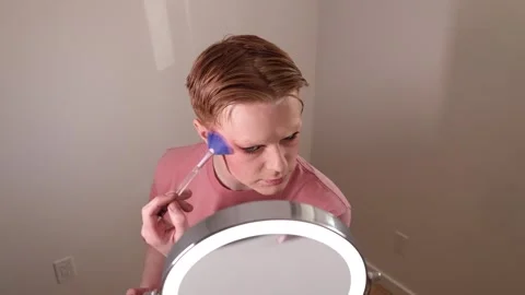 Man Applying Highlighter with Fan Brush in Front of Mirror Stock Footage 310141458