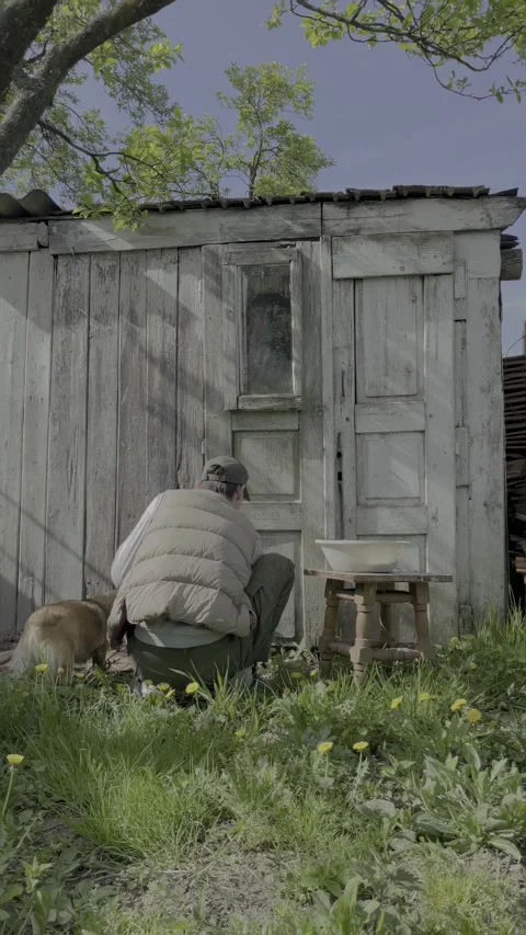 Man applying lime wash to barn exterior in rural setting Stock Footage 334330432