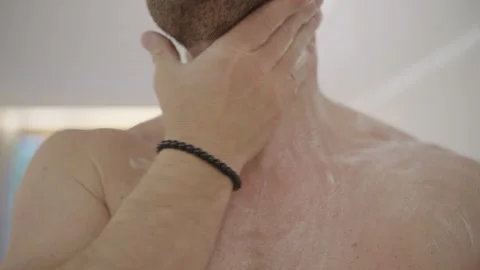 Man applying lotion on his shirtless torso and massaging his skin for daily Stock Footage 335201311