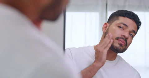 Man applying moisturizer to his beard while standing in front of a mirror. Stock Footage 270505249