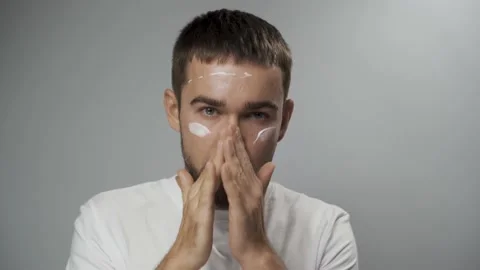 Man is applying moisturizing cream on his face Stock Footage 233517971