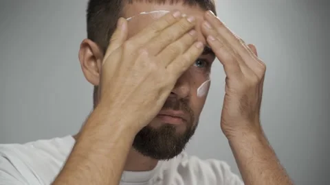 Man is applying moisturizing cream on his face Stock Footage 233520325