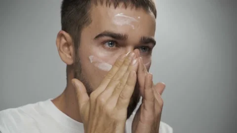 Man is applying moisturizing cream on his face Stock Footage 233520807