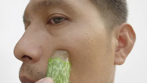 Man applying moisturizing from fresh Aloe vera leaf to his face. Stock Footage 235815456