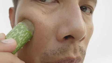 Man applying moisturizing from fresh Aloe vera leaf to his face. Stock Footage 235815622