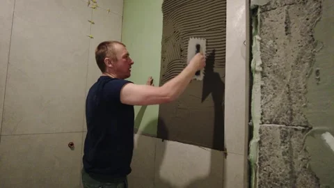 Man applying mortar on wall for tile installation in home renovation project ear 스톡 동영상 332506140