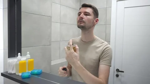 Man applying perfume in front of a bathroom mirror. Personal care products Stock-Footage 283931608