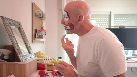 Man applying professional clown make-up in front of a mirror Video stock 323804429