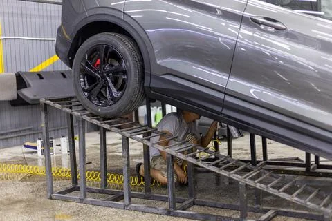 Man applying rust prevention solution under modern grey car Foto stock