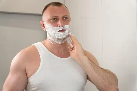 Man applying shaving foam on face before grooming routine Stock Photos