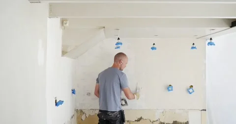 Man applying smoothing plaster on old wall. DIY renovation: Smoothing plaster on Stock Footage 246554291