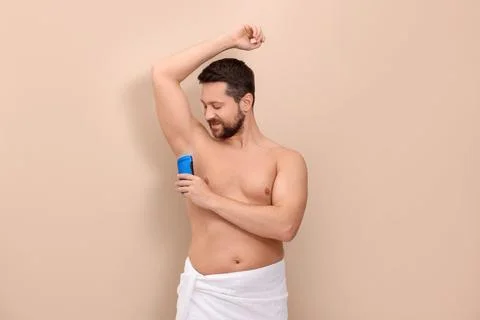 Man applying solid deodorant on beige background 库存照片