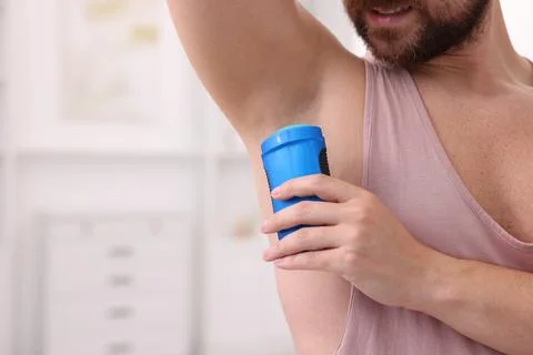 Man applying solid deodorant at home, closeup. Space for text Stockfoto's