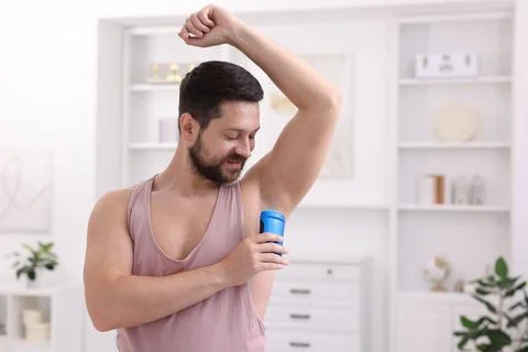 Man applying solid deodorant at home. Space for text Stockfoto's