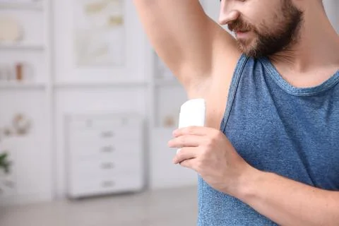 Man applying solid deodorant at home, closeup. Space for text Stockfoto's