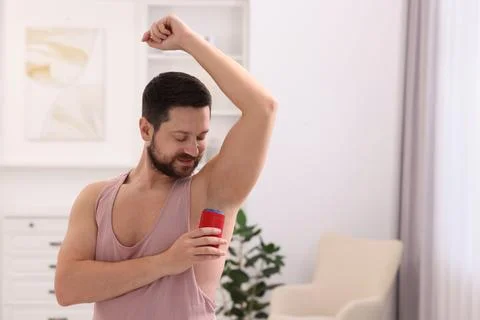 Man applying solid deodorant at home. Space for text Stockfoto's