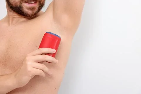Man applying solid deodorant on white background, closeup. Space for text Stockfoto's