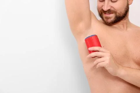 Man applying solid deodorant on white background, closeup. Space for text 스톡 사진