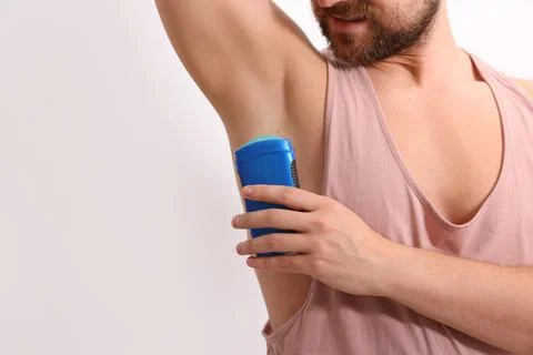 Man applying solid deodorant on white background, closeup. Space for text Stock Photos