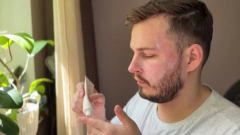 Man applying SPF face cream at home in front of mirror Stock Footage 311313962