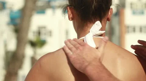 Man applying sun block lotion on woman's back, steadicam shot Видео 10881661