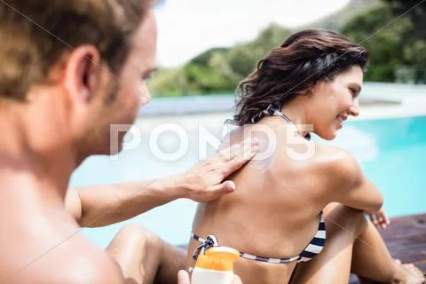 Man applying sunscreen on back of her woman Stock Photos