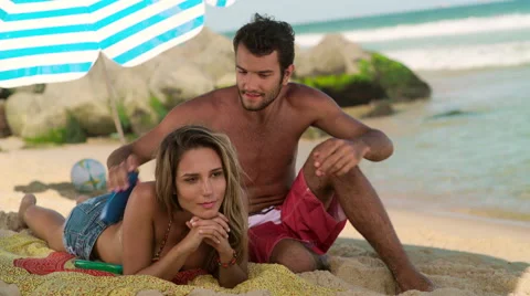 Man applying sunscreen lotion on woman's back at Ipanema beach Stock Footage 59376953