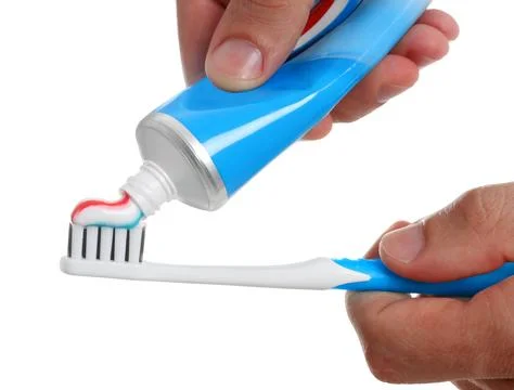 Man applying toothpaste on brush against white background, closeup Stock Photos