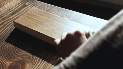 Man applying wood stain. Applying oil on a wooden board with a sponge. Stock Footage 166330747
