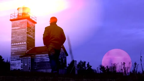 Man approaches a lighthouse at dusk 스톡 동영상 137634314