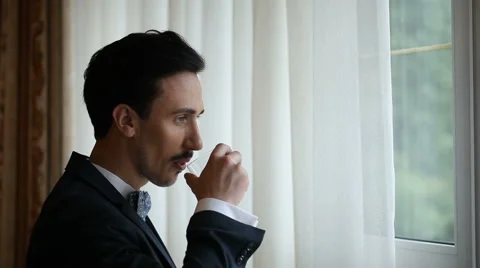 The man approaches a window and drinks whisky Stock Footage 46168811