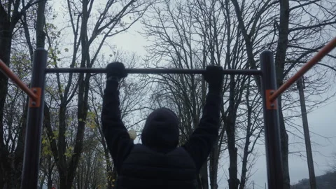 Man Approaching Pull-Up Bar and Starting Pull-Up in Outdoor Park, Back View Stock Footage 326928949