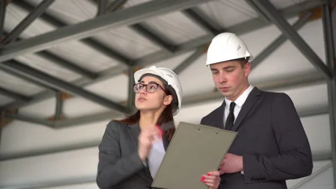 The man approves the project. Young man and woman in helmets with documents at a Stock Footage 134267252