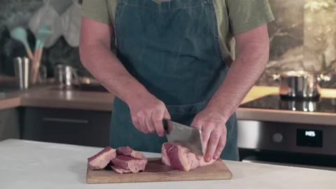 Man in an apron cuts beef with a knife. Stock Footage 161820354