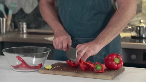 Man in an apron cuts a red bell pepper with a knife. Stock Footage 161824591