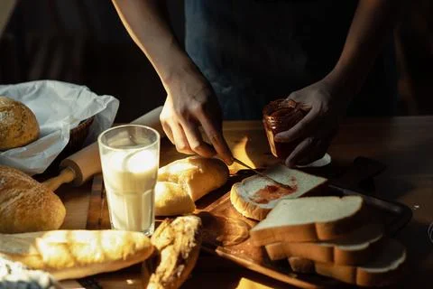 Man in apron preparing breakfast and spreading raspberry jam on slice of bread Stock Photos