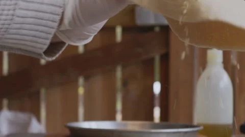 A man in an apron is rolling out pizza dough on a table sprinkled with flour. On Stock Footage 259179441