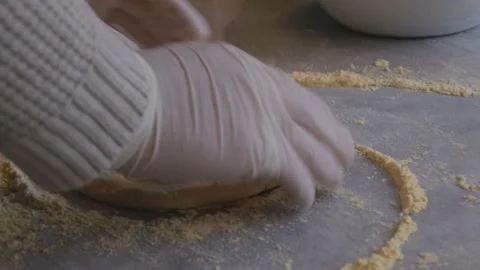 A man in an apron is spreading tomato paste on a pizza dough base on a table Stock Footage 259405728