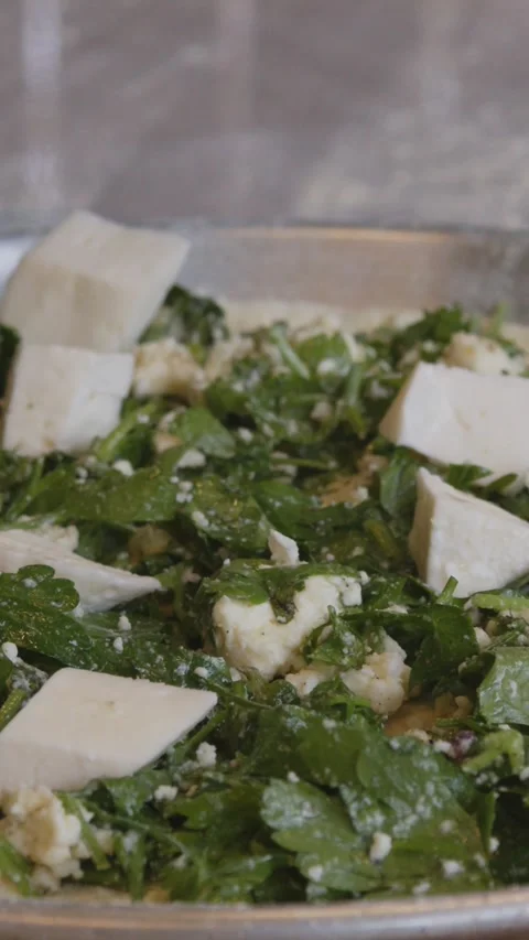 A man in an apron is spreading tomato paste on a pizza dough base on a table Stock Footage 271331388