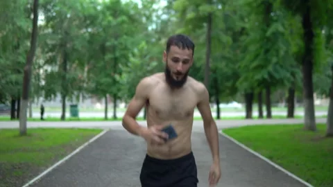 A man of Arab appearance with a beard and without a T -shirt runs in a park with Stock Footage 199292414
