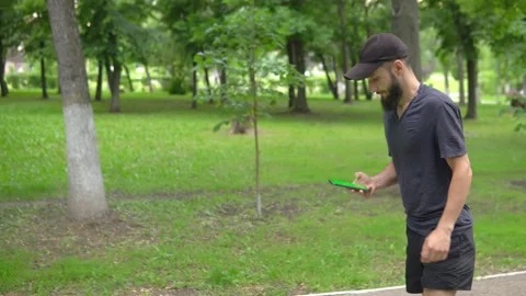 A man of Arab appearance with a beard in a baseball cap runs in a park with a Stock Footage 199292813