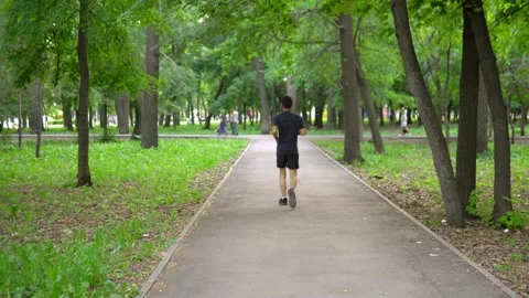 A man of Arab appearance with a beard in a baseball cap runs in a park with a Stock-Footage 199397778