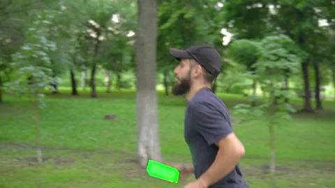 A man of Arab appearance with a beard in a baseball cap runs in a park with a Stock Footage 199398280