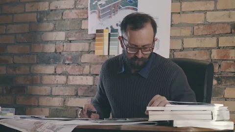 The man is an architect looks at the tablet and makes a sketch Video stock 73669227