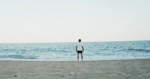 Man with arms raised on a beach during a sunset Stock Footage 135582259