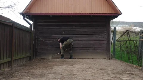 A man in army fatigues is digging in the backyard. Vídeos de archivo 136510795