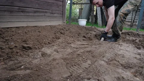 A man in army fatigues is digging in the backyard. Video stock 136511000