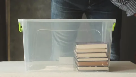 A man arranges books in a plastic box. Stock Footage 249350313